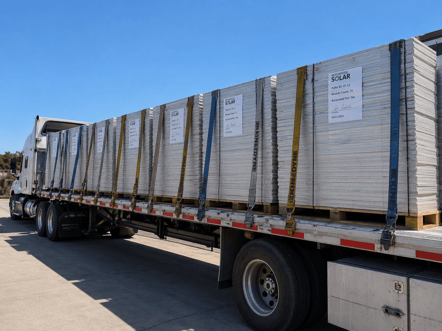 Flatbed truck loaded with palletized solar panels tagged with Repurpose Solar chain-of-custody labels